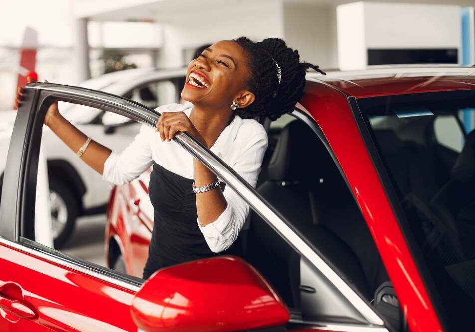 Woman buying the car. Lady in a car salon. Elegant black girl